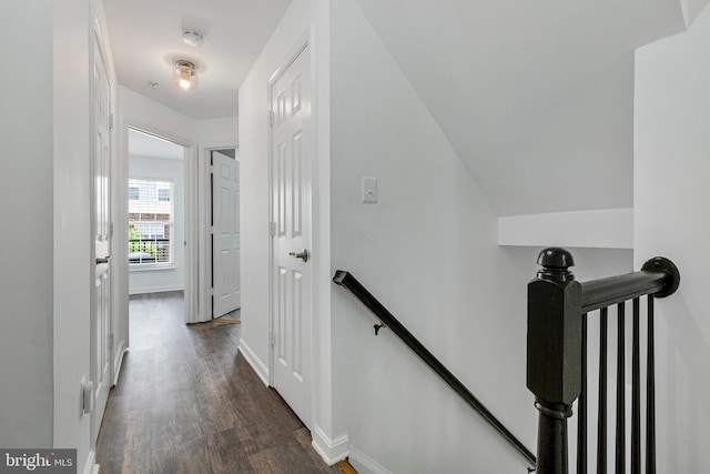 hall with an upstairs landing, dark wood-type flooring, and baseboards