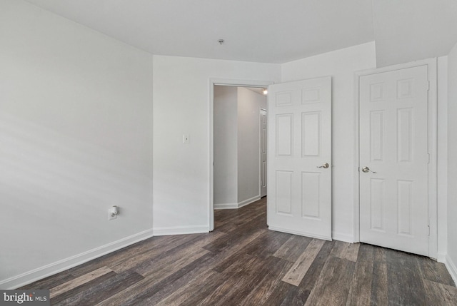 unfurnished bedroom with dark wood finished floors and baseboards