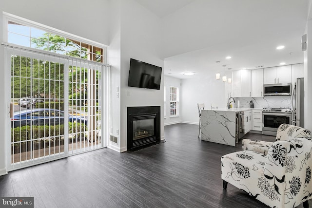 living room featuring dark wood-style floors, baseboards, a glass covered fireplace, and recessed lighting