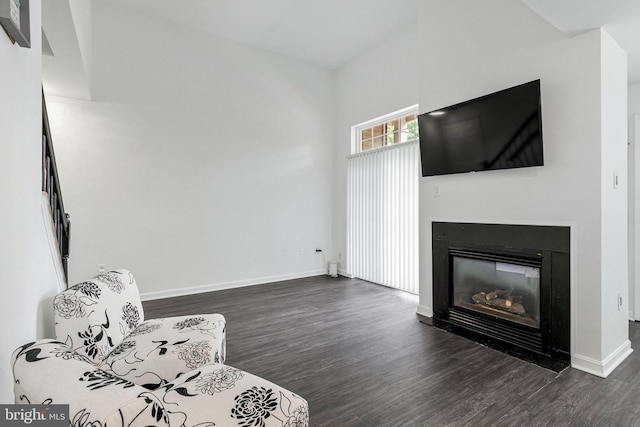 unfurnished living room featuring dark wood-style floors, a glass covered fireplace, and baseboards
