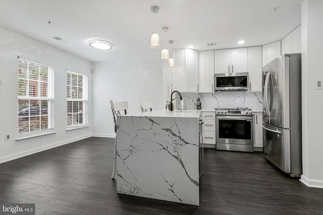 kitchen with stainless steel appliances, a peninsula, dark wood-type flooring, white cabinets, and recessed lighting