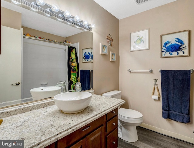 full bathroom with wood finished floors, a shower with shower curtain, toilet, vanity, and baseboards