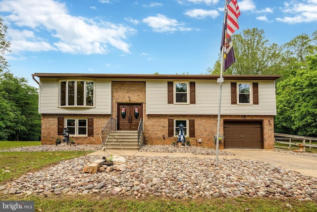 split foyer home with driveway, brick siding, entry steps, and a garage