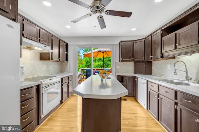 kitchen with a sink, under cabinet range hood, white appliances, dark brown cabinetry, and recessed lighting