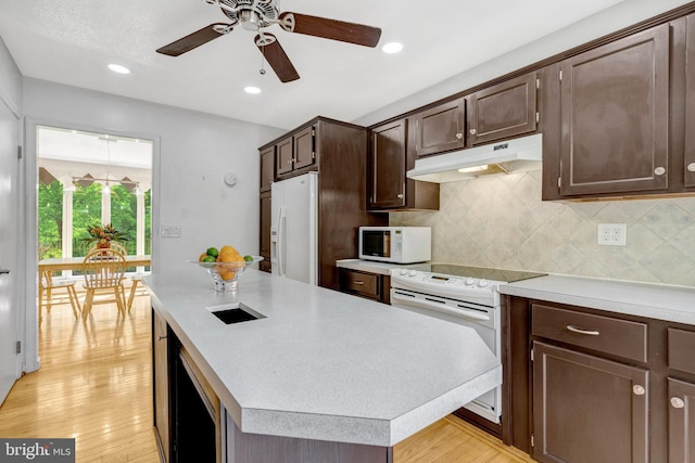 kitchen with white appliances, under cabinet range hood, ceiling fan, dark brown cabinets, and light countertops