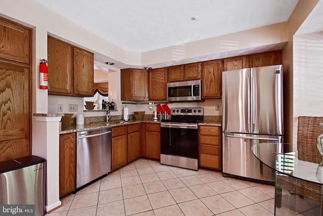 630 Brookedge Ct, Bowie, MD 20721 - kitchen featuring stainless steel appliances, brown cabinetry, light tile patterned floors, and stone counters