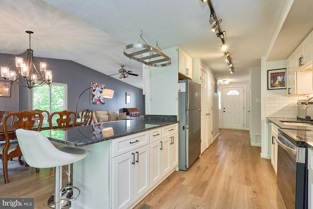 kitchen featuring freestanding refrigerator, dishwasher, white cabinetry, a peninsula, and vaulted ceiling
