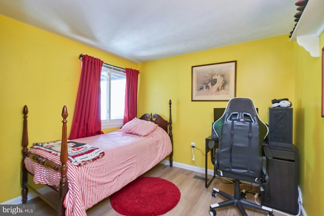 bedroom featuring wood finished floors, baseboards, and a desk