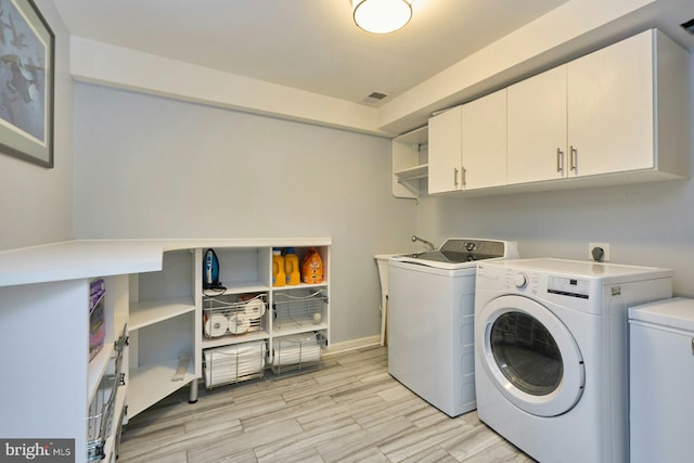 laundry area featuring cabinet space, separate washer and dryer, light wood-style floors, and baseboards