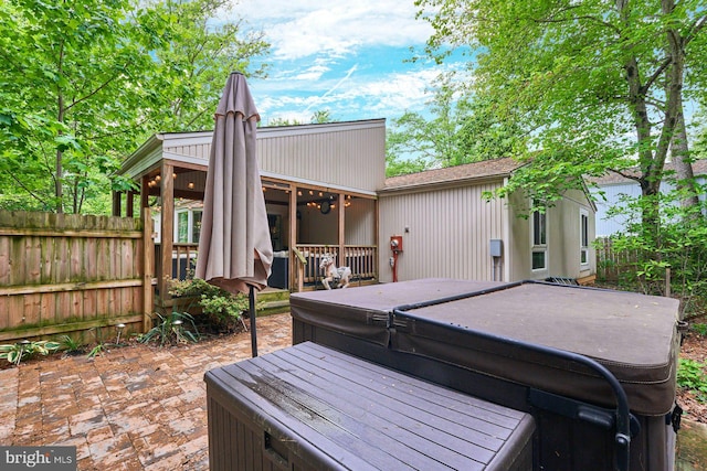 deck with a hot tub, fence, and a patio