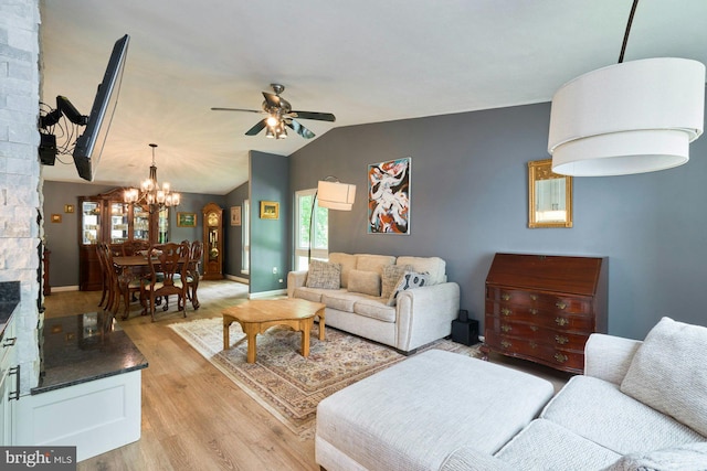 living room featuring light wood-style floors, ceiling fan, a chandelier, lofted ceiling, and baseboards