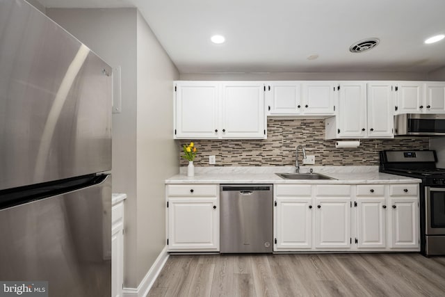 12705 Gordon Blvd Unit 37, Woodbridge, VA 22192 - kitchen with stainless steel appliances, light wood-type flooring, white cabinetry, decorative backsplash, and recessed lighting