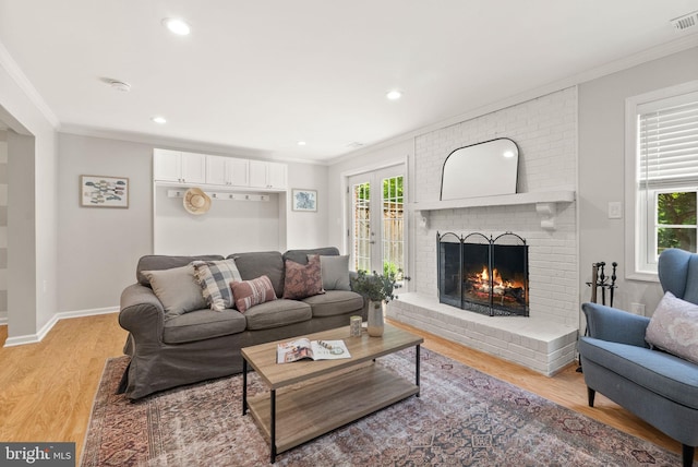 living room with ornamental molding, a brick fireplace, healthy amount of natural light, light wood finished floors, and recessed lighting