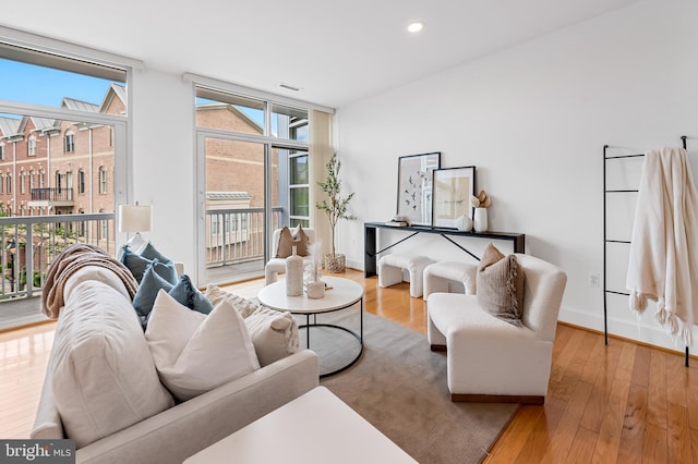 living room with wood finished floors, baseboards, floor to ceiling windows, and recessed lighting