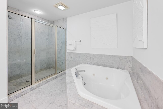 full bath featuring a shower stall, a tub with jets, wainscoting, and tile walls