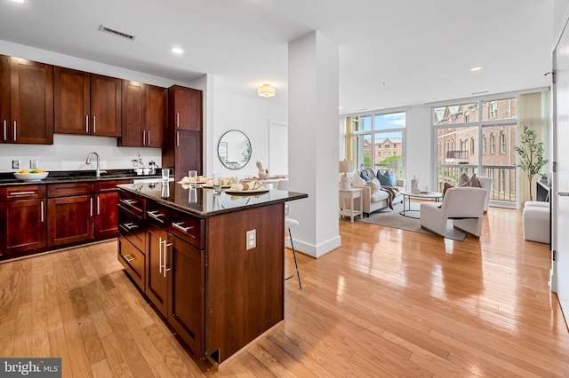 kitchen with healthy amount of natural light, light wood-style flooring, a kitchen breakfast bar, a center island, and recessed lighting