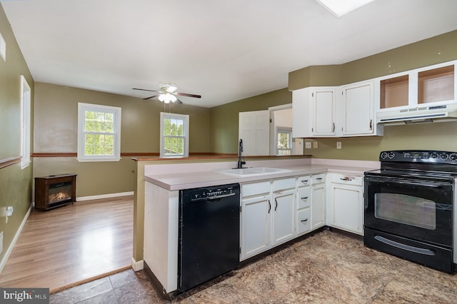 kitchen featuring black appliances, a sink, under cabinet range hood, a peninsula, and white cabinets