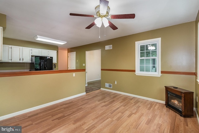 unfurnished living room featuring light wood finished floors, a ceiling fan, and baseboards