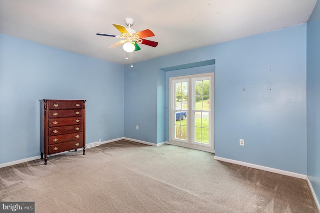 spare room with carpet floors, a ceiling fan, and baseboards