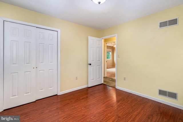 unfurnished bedroom with dark wood finished floors, baseboards, and a closet
