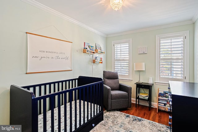 bedroom featuring crown molding, wood finished floors, baseboards, and a nursery area