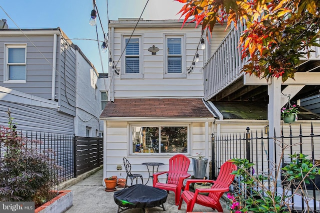 back of house with an outdoor fire pit, roof with shingles, and a patio