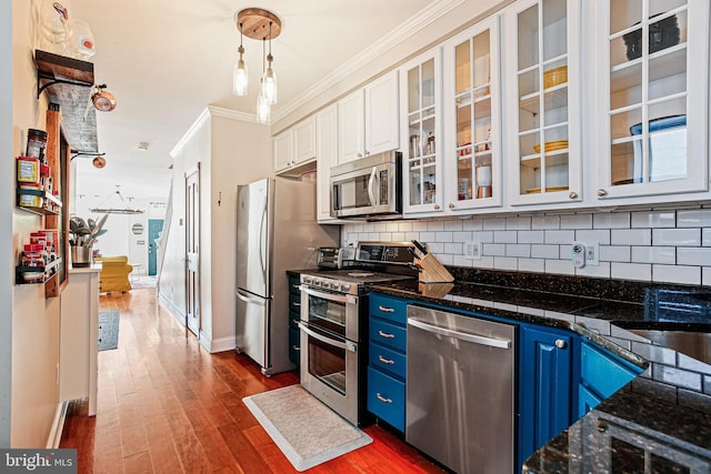 kitchen featuring stainless steel appliances, blue cabinets, ornamental molding, tasteful backsplash, and dark wood-type flooring