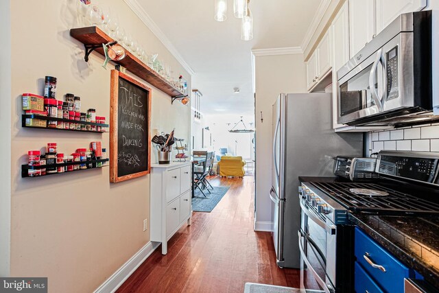 kitchen with stainless steel appliances, ornamental molding, white cabinetry, dark wood-type flooring, and backsplash