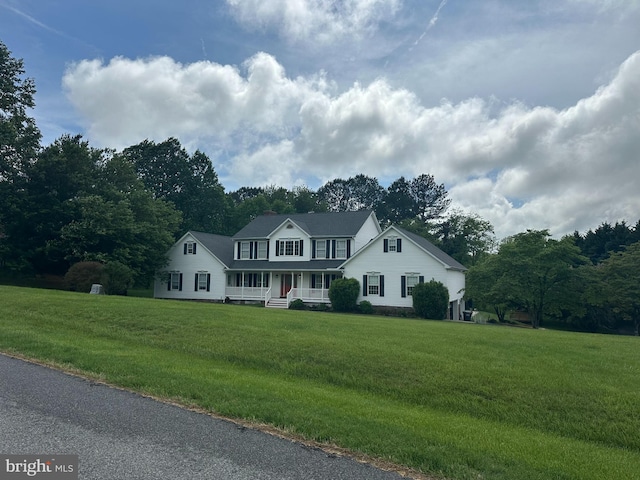 colonial inspired home featuring a porch and a front lawn