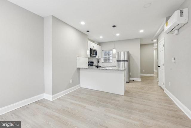 kitchen featuring stainless steel appliances, an AC wall unit, a peninsula, white cabinets, and recessed lighting
