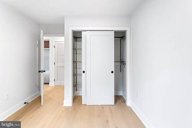 unfurnished bedroom with light wood finished floors, a closet, and baseboards