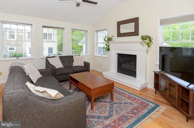 living room with light wood finished floors, ceiling fan, vaulted ceiling, plenty of natural light, and a brick fireplace