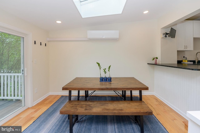 dining space with light wood-style flooring, an AC wall unit, a skylight, baseboards, and recessed lighting