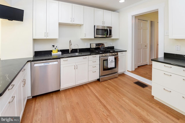 kitchen featuring appliances with stainless steel finishes, a sink, white cabinets, light wood-type flooring, and recessed lighting
