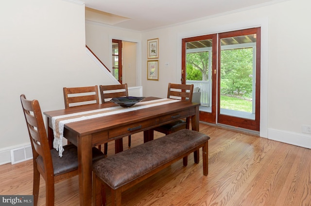 dining area featuring light wood finished floors, ornamental molding, and baseboards