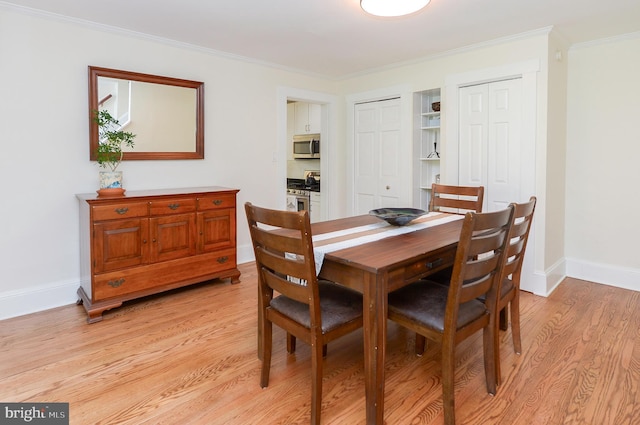 dining space featuring light wood-style floors, baseboards, and crown molding