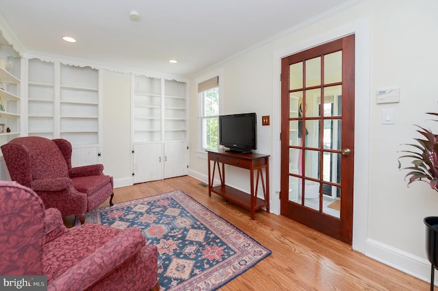 living area with wood finished floors, ornamental molding, baseboards, built in shelves, and recessed lighting