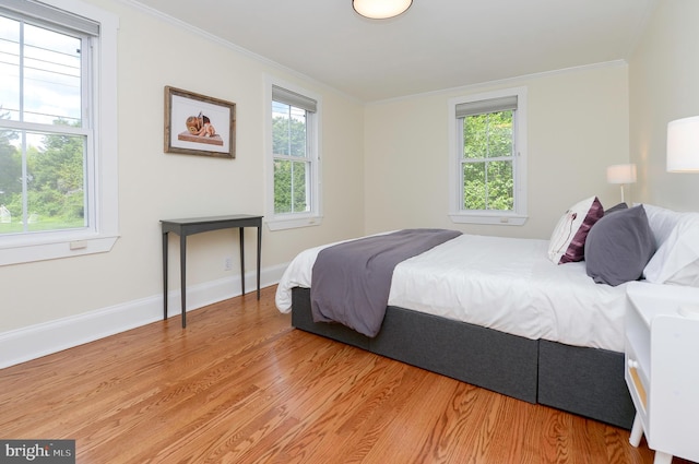 bedroom featuring multiple windows, wood finished floors, crown molding, and baseboards