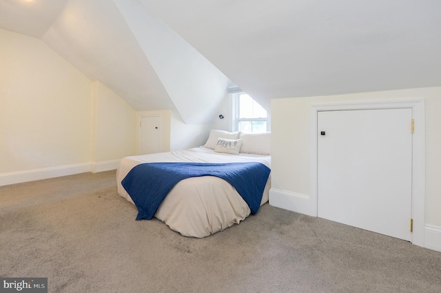 carpeted bedroom featuring vaulted ceiling and baseboards