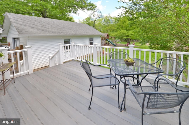 deck featuring a playground, outdoor dining area, and a yard