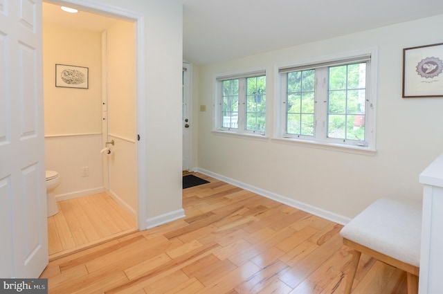 hallway featuring light wood finished floors and baseboards