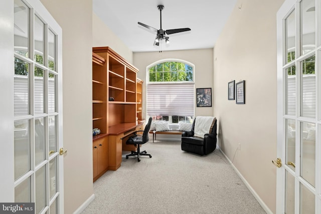 carpeted office space featuring a ceiling fan, baseboards, french doors, and built in desk