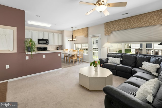 living room with a chandelier, plenty of natural light, light colored carpet, and a ceiling fan