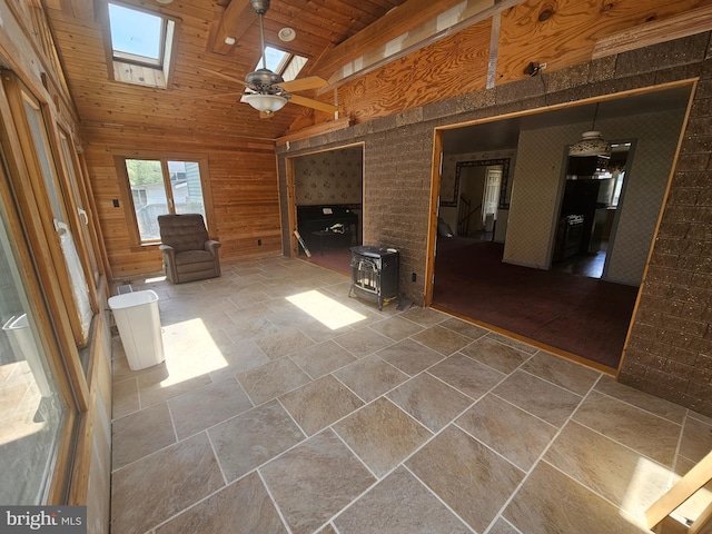 7023 Dolphin Rd, Lanham, MD 20706 - unfurnished living room with a wood stove, a skylight, stone tile flooring, high vaulted ceiling, and wood walls
