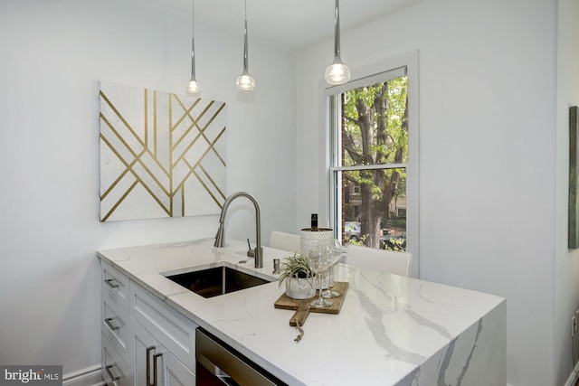 kitchen featuring a sink, pendant lighting, light stone countertops, and white cabinetry