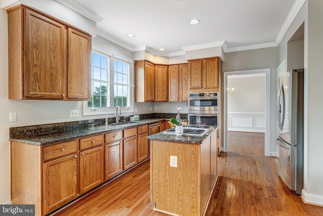 16028 Kings Mountain Rd, Woodbridge, VA 22191 - kitchen featuring stainless steel appliances, a sink, light wood-type flooring, a center island, and dark stone counters