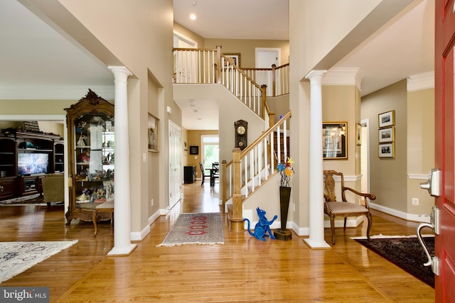 8931 Kiger St, Lorton, VA 22079 - foyer entrance featuring decorative columns, light wood finished floors, stairs, crown molding, and baseboards