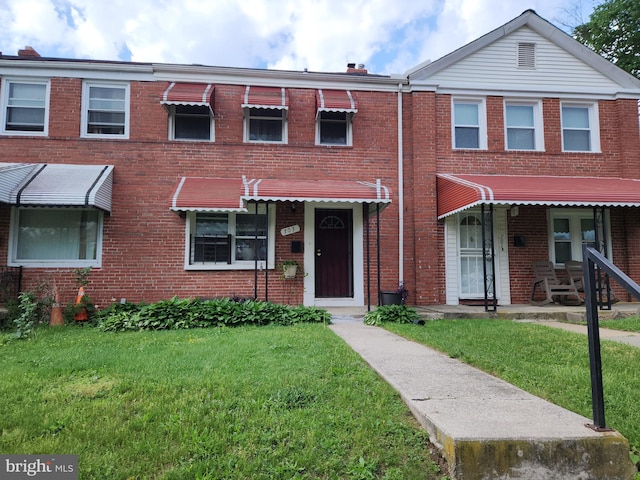 multi unit property with a front lawn and brick siding