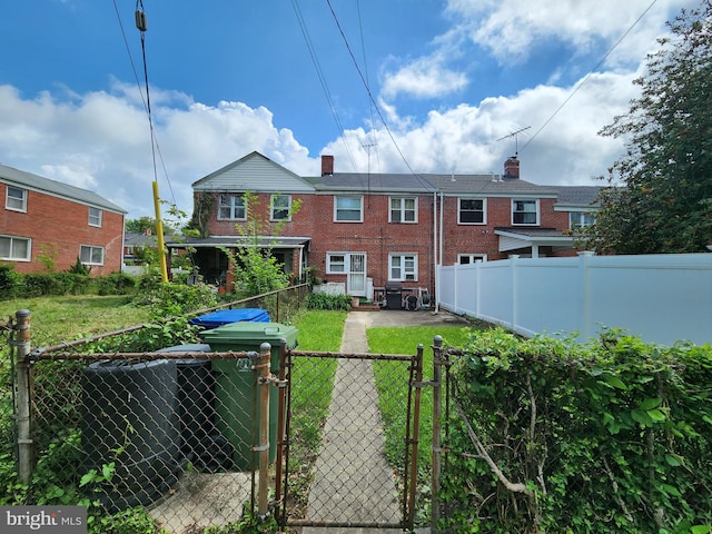 rear view of property featuring a gate and brick siding