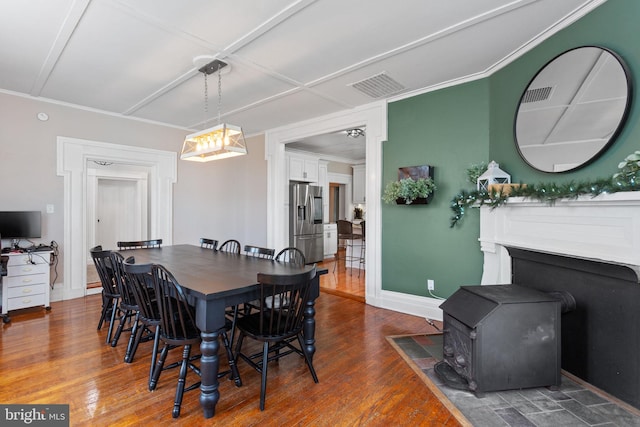 644 Early Dr, Broadway, VA 22815 - dining room featuring a wood stove, wood finished floors, crown molding, and baseboards